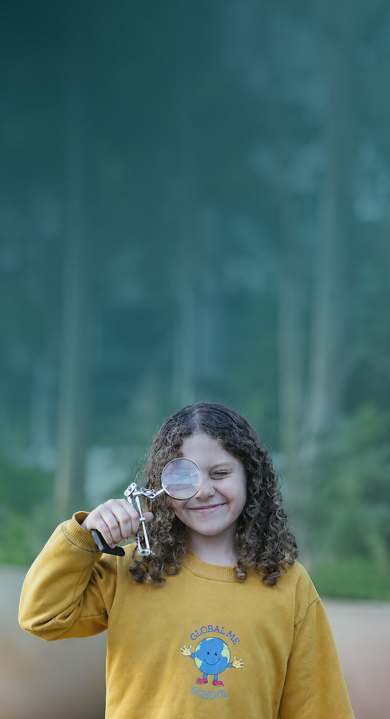 Aluna da Global Me School sorrindo, com uma lupa