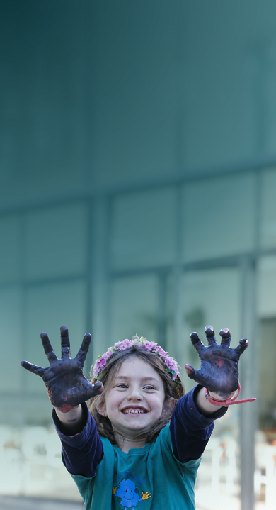 Criança da Global Me School sorrindo, com as mãos pintadas